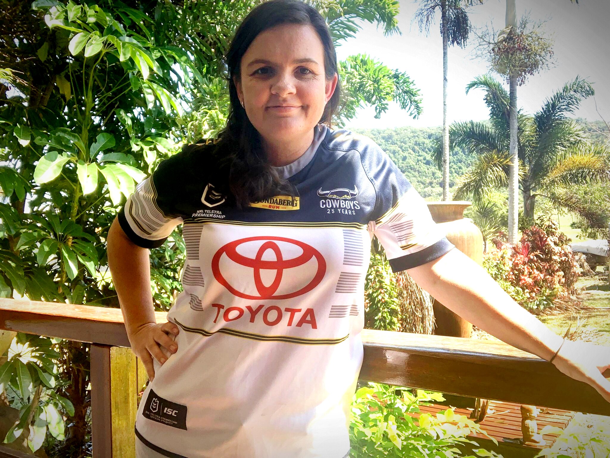 A woman in a Cowboys jersey stands on a balcony.