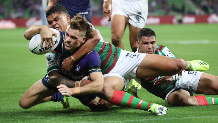 Melbourne Storm's Ryan Papenhuyzen dives for the tryline with South Sydney Rabbitohs' Latrell Mitchell around his neck.
