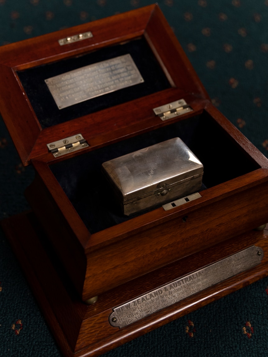 A wooden box containing a small silver razor case designed as a soccer trophy for Australia