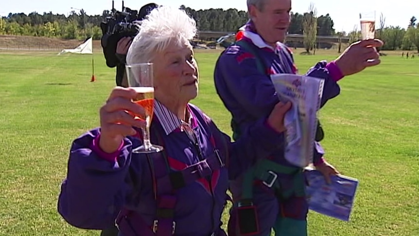 A woman holds a champagne glass standing outside 