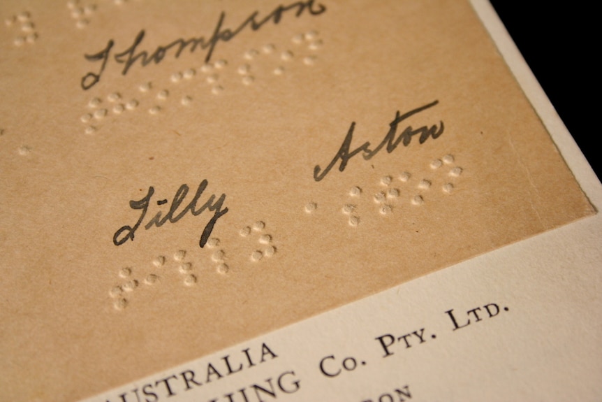 A close up of a page with braille marks and a written signature of Tilly Aston.