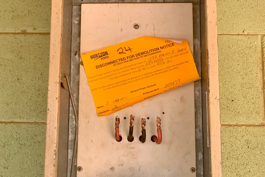 An orange sticker on a power box saying 'Disconnected for demolition notice' 