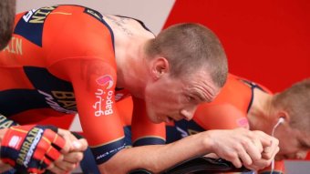Rohan Dennis strains and looks forward as he pedals on an exercise bike.