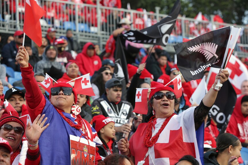 Les fans de la ligue de rugby des Tonga et de la Nouvelle-Zélande agitent des drapeaux avant un test.