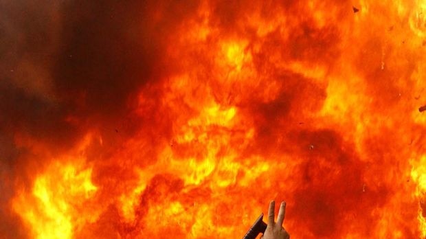 An Iranian opposition supporter gestures next to a burning police motorcycle