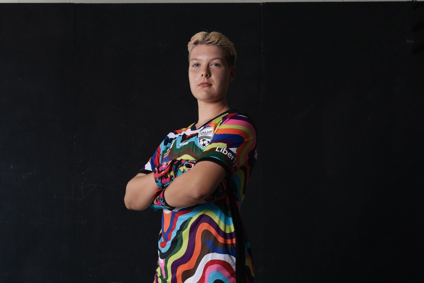 Grace Wilson wearing colourful jersey with arms crossed looking into camera. 