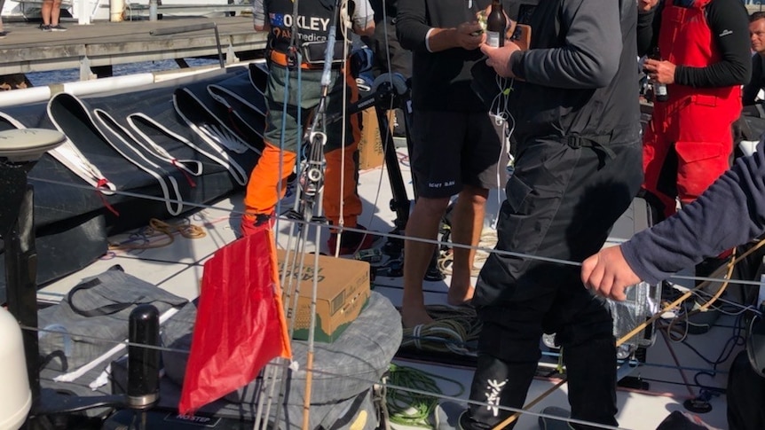 A small red protest flag on a yacht with crew members on deck
