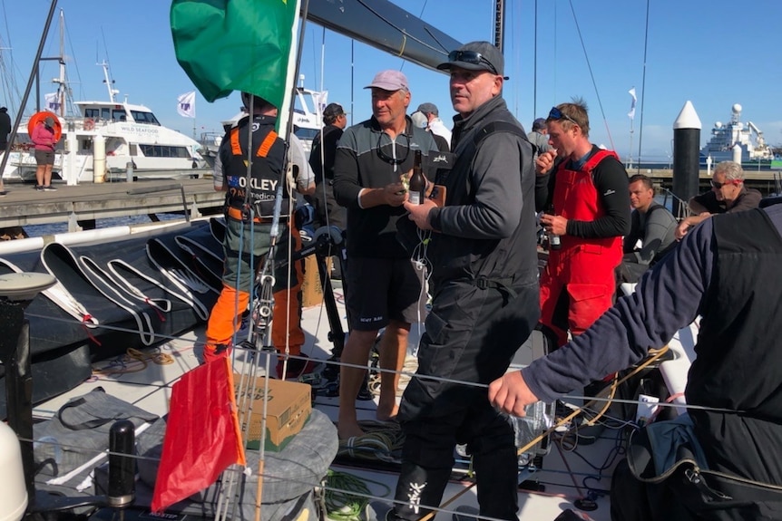 A small red protest flag on a yacht with crew members on deck