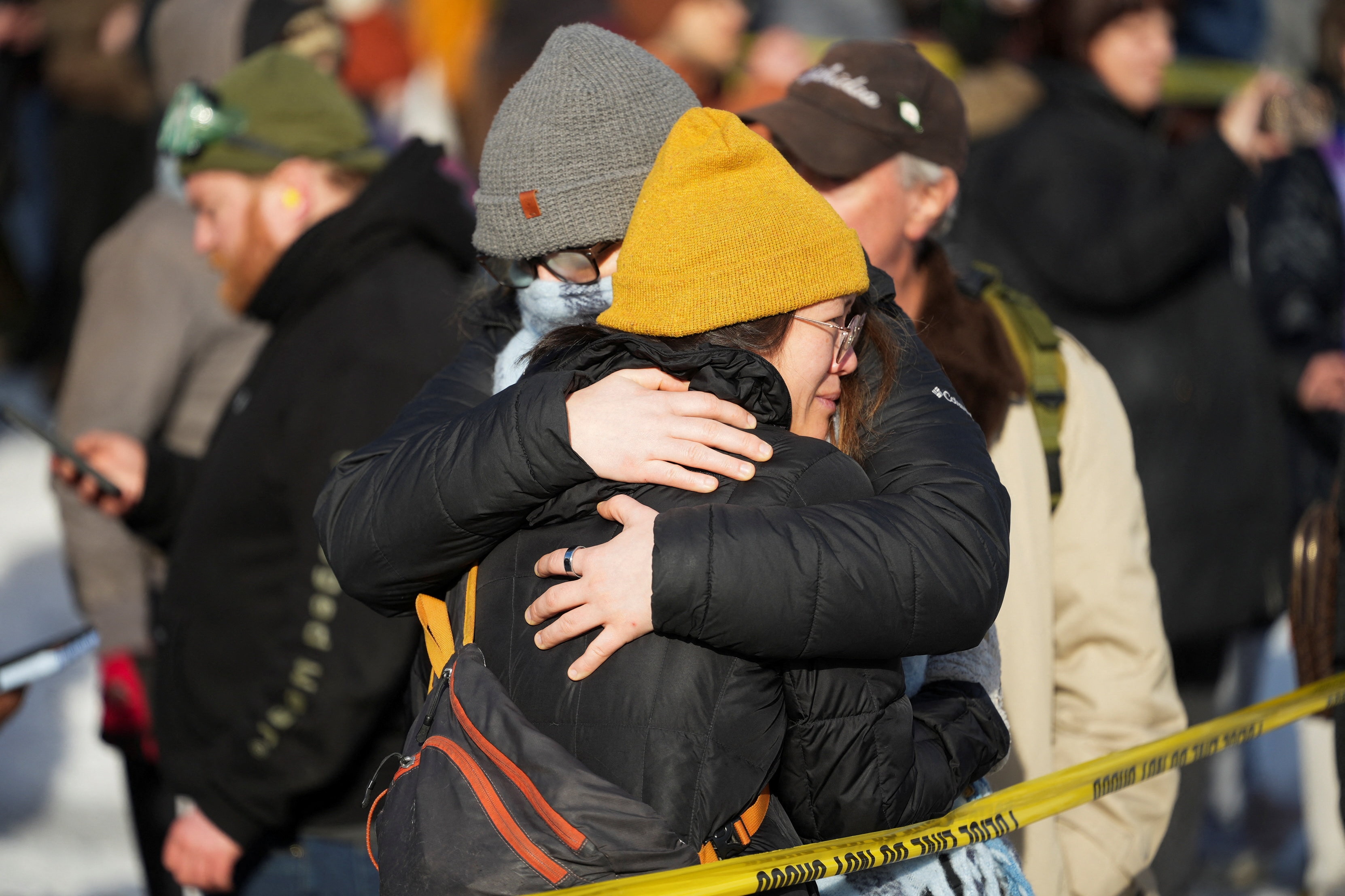 Dos personas se abrazan y usan sombreros.