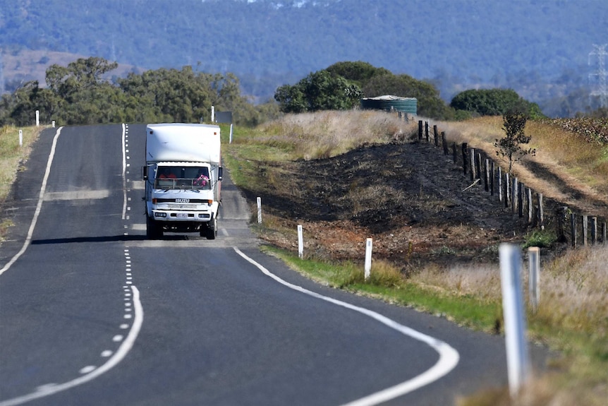 The charred remains of a fire by the side of a road caused by a crash between a car and a truck.