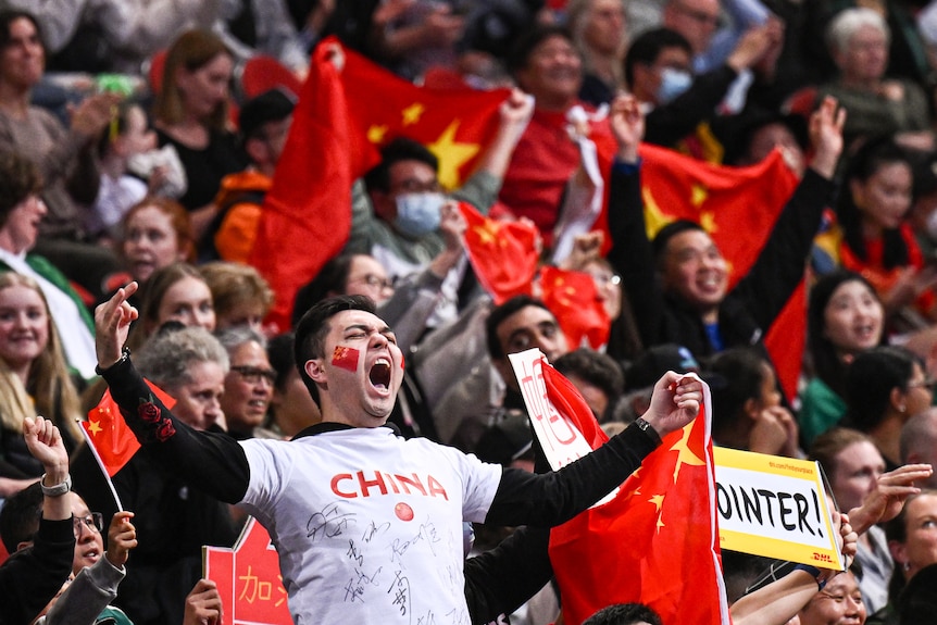 A fan with 'China' on his t-shirt screams with passion, while other Chinese fans cheer in the background