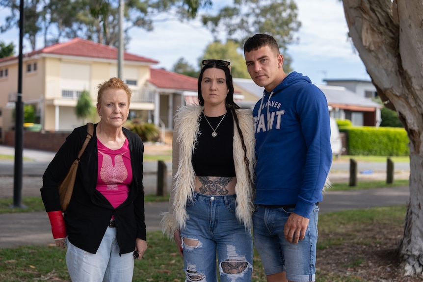 Jackie, Lacey and Severio stand together in a park, looking serious.