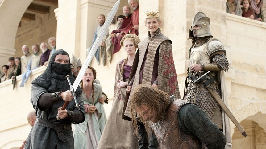 Ned Stark bows his head as he waits to be decapitated by his own sword. Joffrey, Cersei and Sansa watch on.