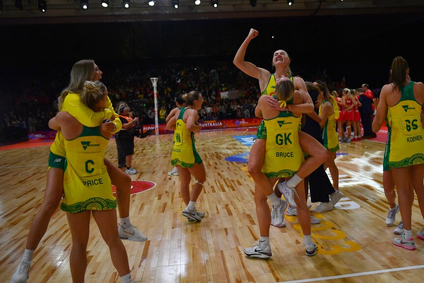 Australian netballers embrace in celebration on court after the end of the Netball World Cup final.