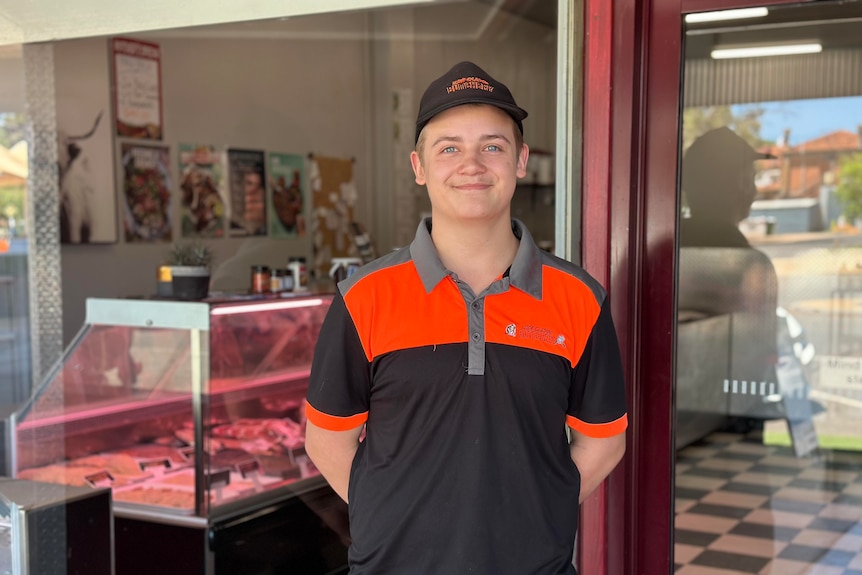 17-year-old boy in cap and butcher uniform standing at butcher