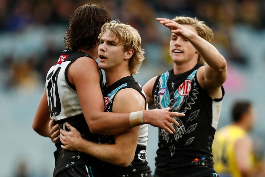 Three Port Adelaide AFL players celebrate a goal against Richmond.
