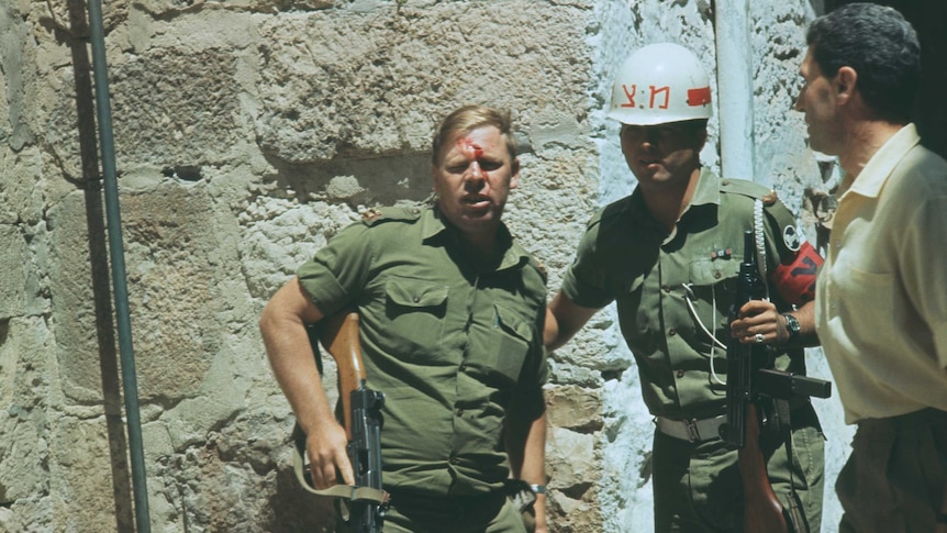 An Israeli solider is aided by fellow sliders, he has blood on his face