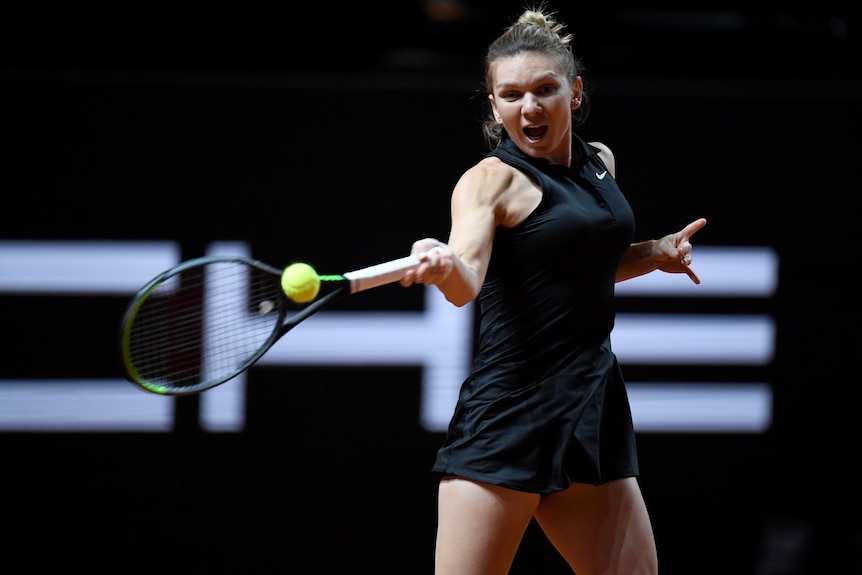 A tennis player grimaces as her racquet connects with the ball for a forehand during a match.