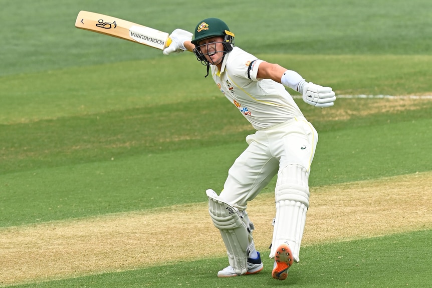 Marnus Labuschagne smiles and swings his bat behind him