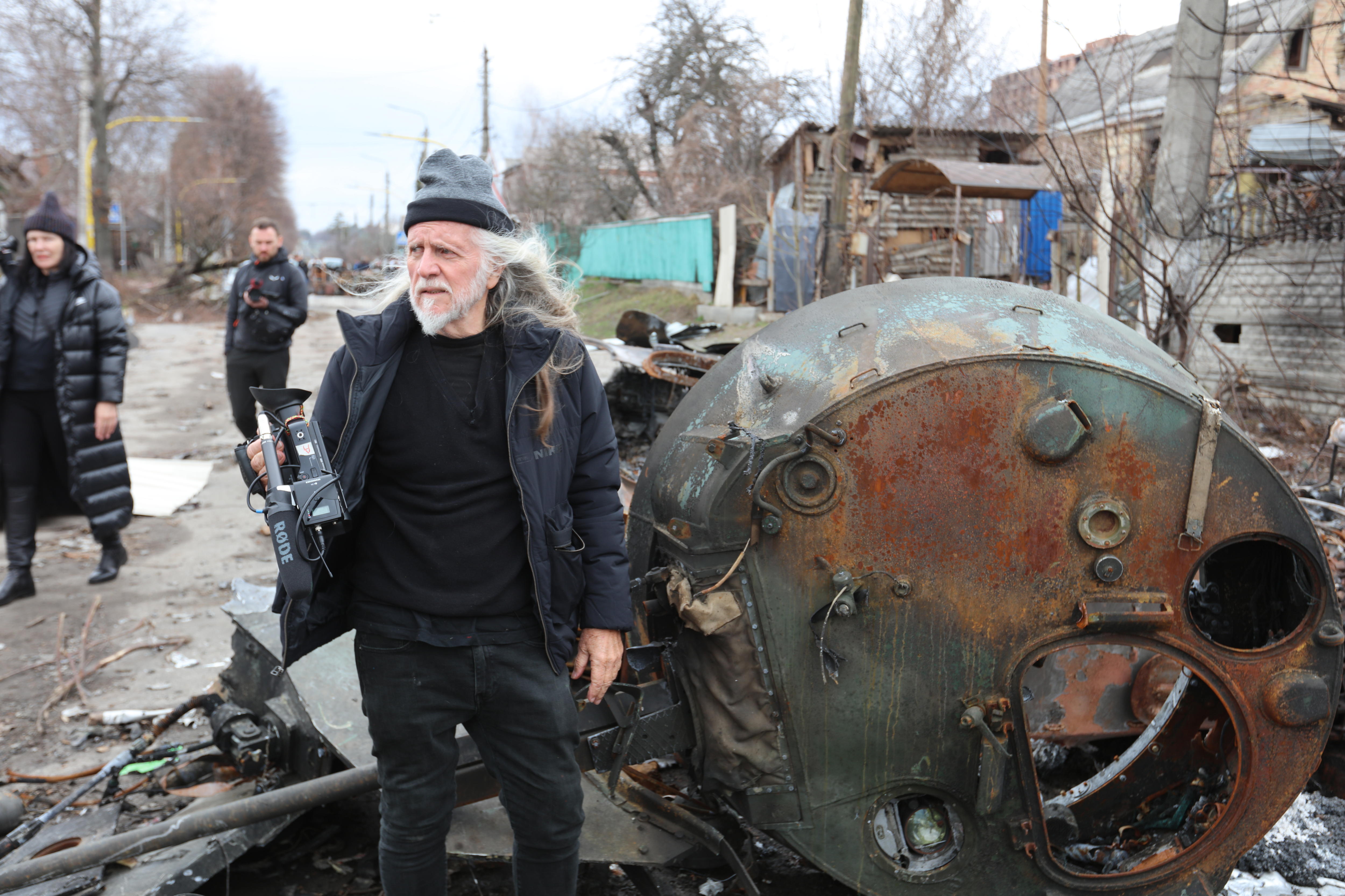 Un hombre lleva una cámara de vídeo entre los escombros de la guerra.