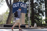 Young man passes in front of QUT sign