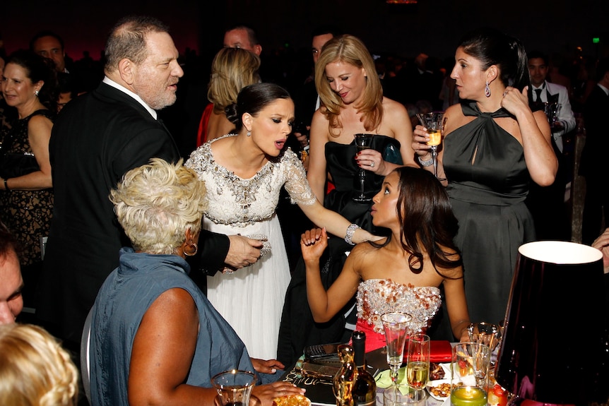 Harvey Weinstein surrounded by women in evening gowns