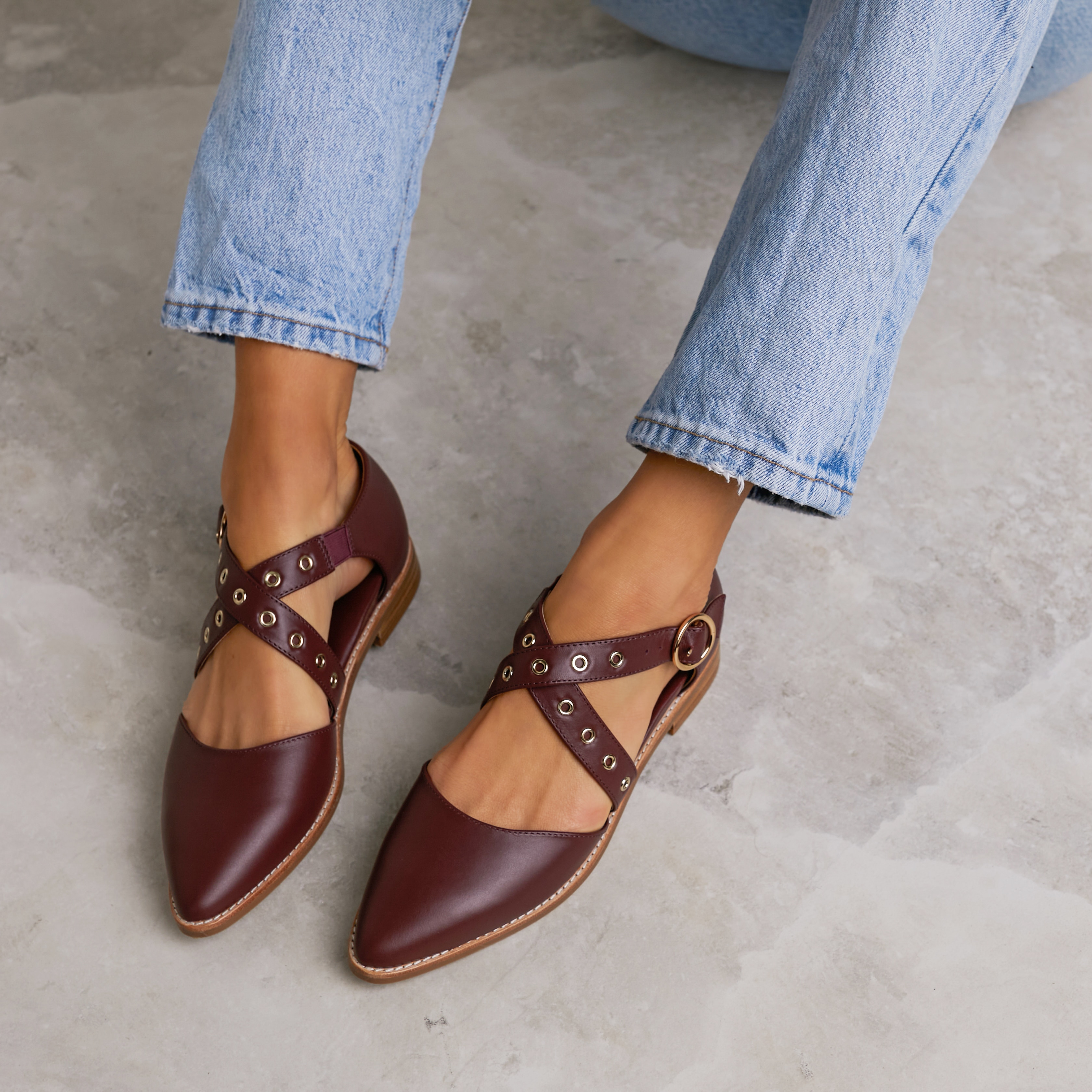 A pair of burgundy leather shoes, modelled by a woman.