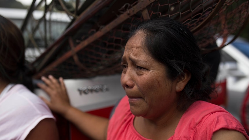 A grieving relative waits outside the Virgen de Asuncion home for teens in San Hose Pinula, Guatemala