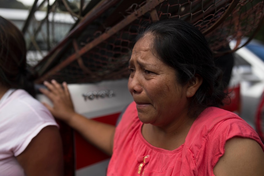 A grieving relative waits outside the Virgen de Asuncion home for teens in San Hose Pinula, Guatemala