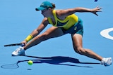 Ash Barty leans at full stretch to get her racquet to the ball during a point at the Olympics.