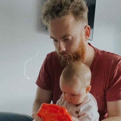 A man with a beard holding a baby