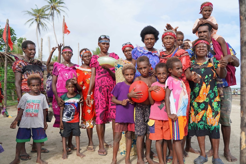 A group of Papua New Guinean locals across generations wearing colourful clothing.