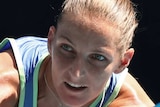 A female tennis player crouches as she plays a backhand at the Australian Open.