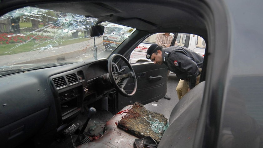 A policemen inspects a police car covered in blood after the attack.