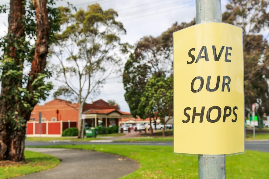 A sign reading "save our shops" is taped to a lightpole