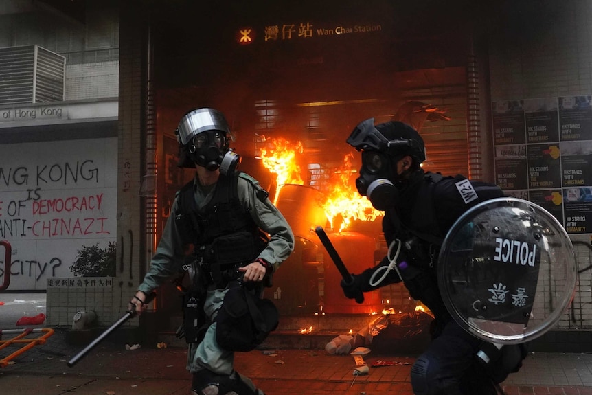 Riot police in action in front of a shop on fire
