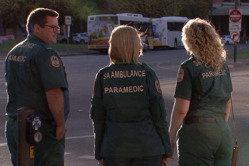 Three paramedics wait at pedestrian crossing