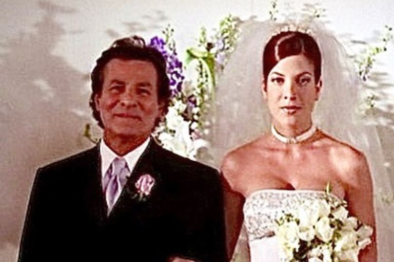 A young bride stands with an older man.