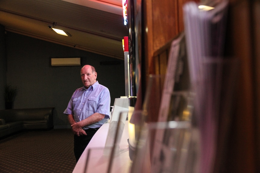 A man stands in a dark theatre foyer