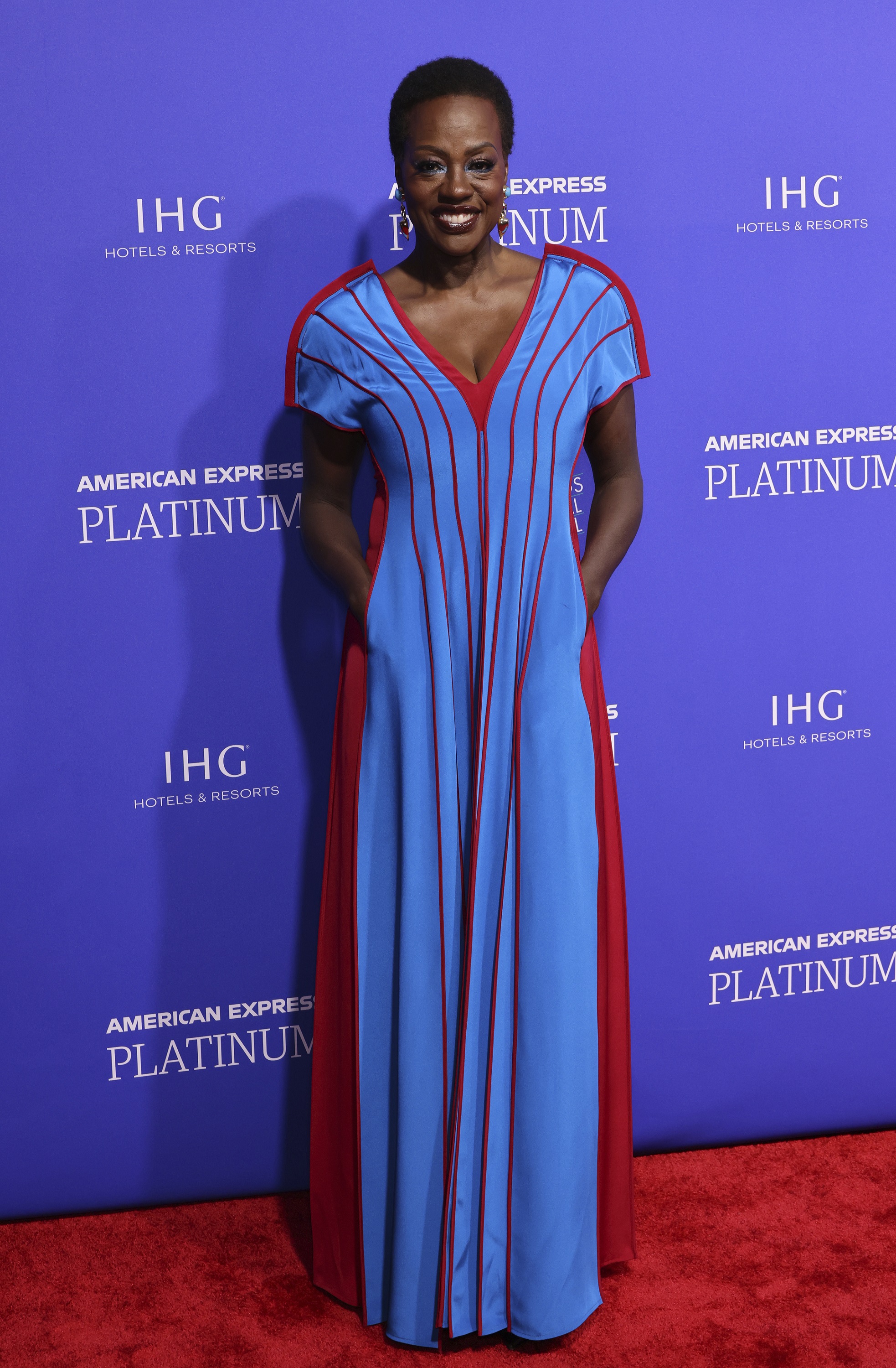 Viola Davis wearing a bright light blue floor-length gown with red seams and panels, pockets and short sleeves