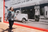 Morawa shire president Karen Chappel walks down the main street of Morawa in front of a giant historical photo of the township.