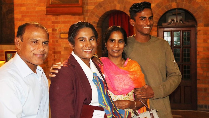 Soumiga Gopalakrishnan, dressed in her school uniform, with her family at her graduation mass in Brisbane.