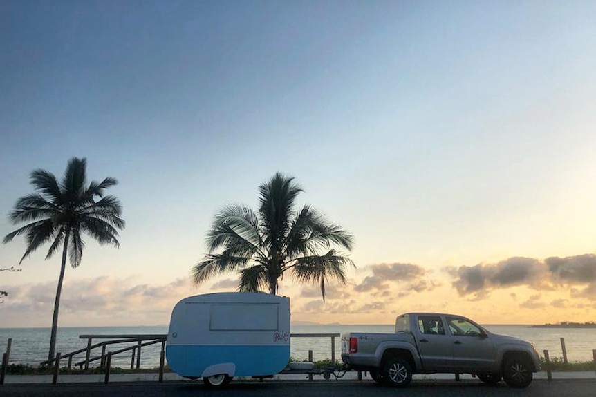 Coffee van Ruby hitched up to four-wheel-drive ute, parked on side of road with palm trees in view in Yeppoon near Rockhampton.