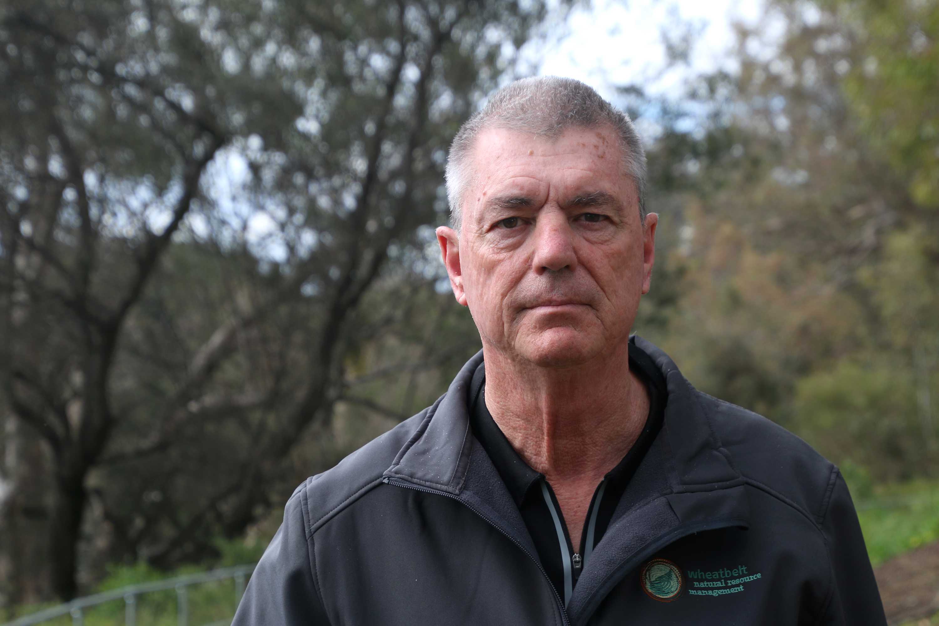 Headshot of a man with a bush background.