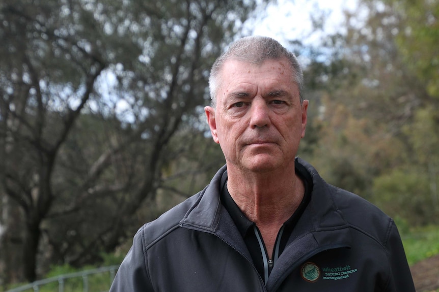 Headshot of a man with a bush background.