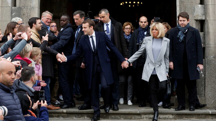 Emmanuel Macron and wife Brigitte leave a polling station.
