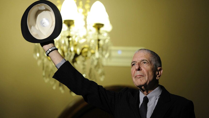 Leonard Cohen holds his hat up to the crowd
