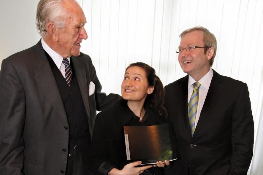 Patricia Karvelas looks up at Malcolm Fraser, who is standing on her right. On her left stands Kevin Rudd