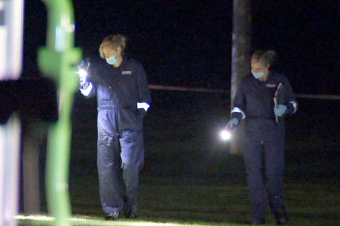 Two forensic officers with torches in Mayer Park.