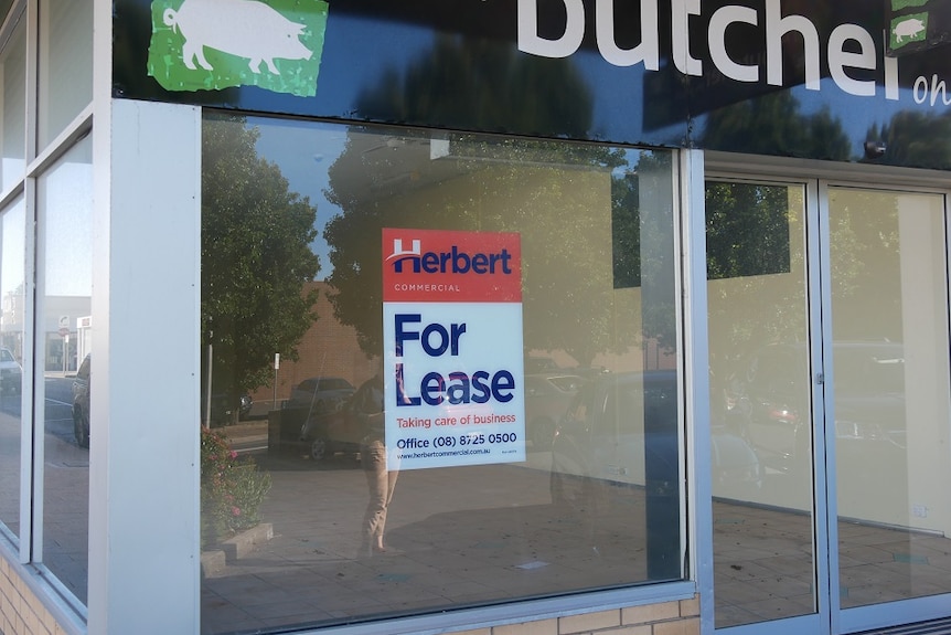 An empty shop with a "my butcher" sign at the top and a "for lease" sign in the window.